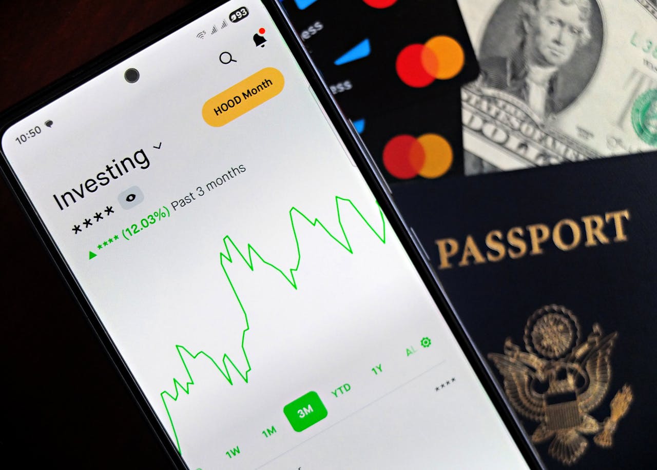 Smartphone showing stock market app with travel essentials: passport, money, and cards.
